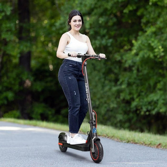 Woman riding an electric scooter on a road with greenery in the background