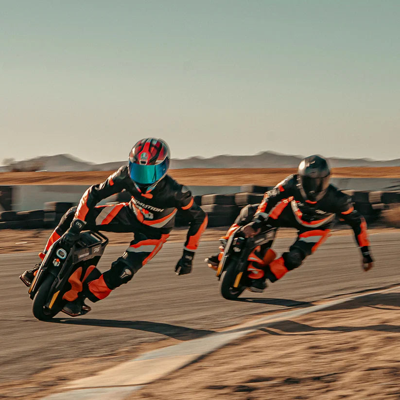 Two motorcyclists racing on a track with a desert landscape in the background
