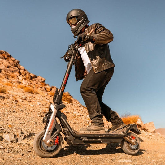 Person riding a scooter in a desert landscape with a clear blue sky
