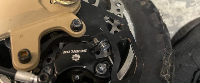 Mechanical disc brake caliper, rotor and brake cable on an electric scooter wheel at Wilson's Elmhurst shop