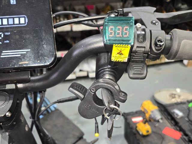 Battery gauge and voltmeter on an electric scooter's handlebar during a battery check at a Wilson's shop