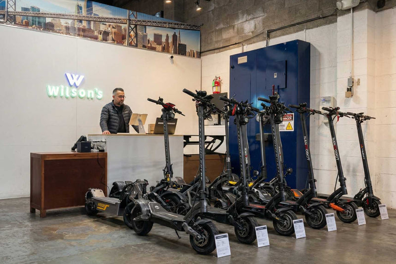 Row of electric scooters in front of a reception desk with 'Wilson's' branding.
