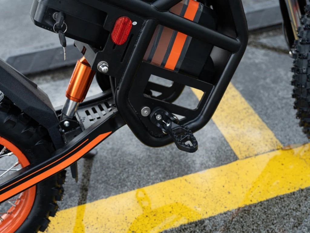 Close-up of a motorcycle's rear section with orange and black design on a road.