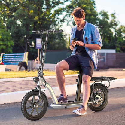 Man using a smartphone while sitting on an electric scooter in a park-like setting.