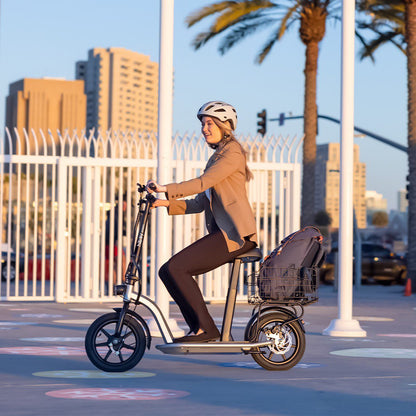 Person riding an electric scooter with a helmet on a city street with palm trees in the background.