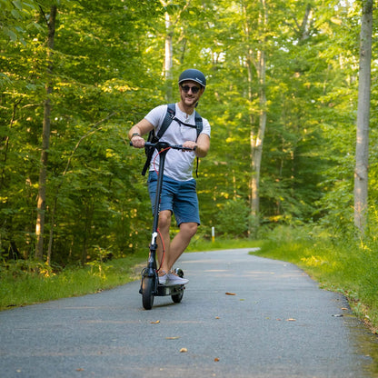 Man riding an electric scooter on a path surrounded by trees