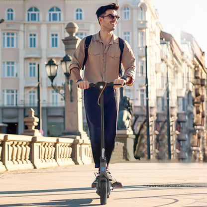 Man riding an electric scooter in an urban setting with buildings in the background