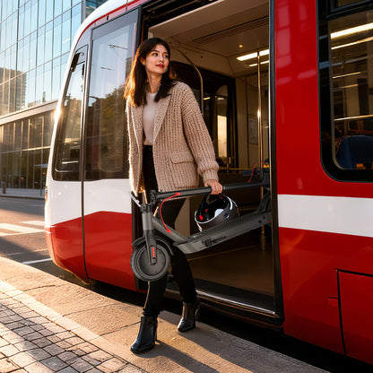 Woman getting off a red and white train holding a black scooter.