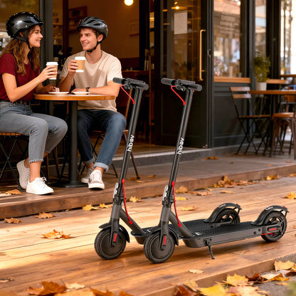 Two electric scooters on a sidewalk with people sitting at a table in the background.