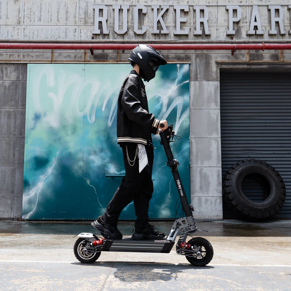 Person with a helmet and black scooter in front of a building with 'Rucker Park' sign.