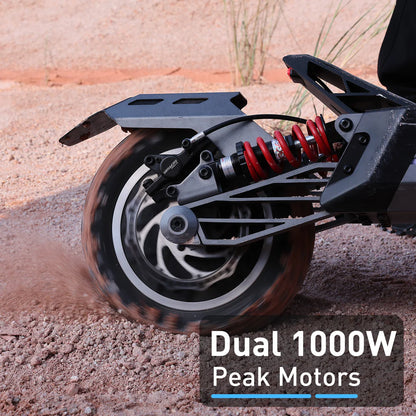 Close-up of a motorcycle wheel with 'Dual 1000W Peak Motors' text on a gravel surface.