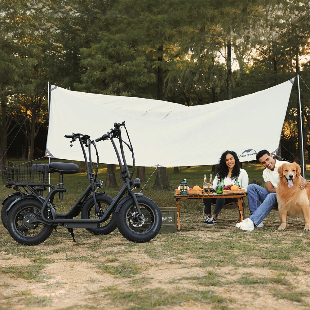 Two electric scooters parked outdoors with a couple and their dog near a table under a white canopy.