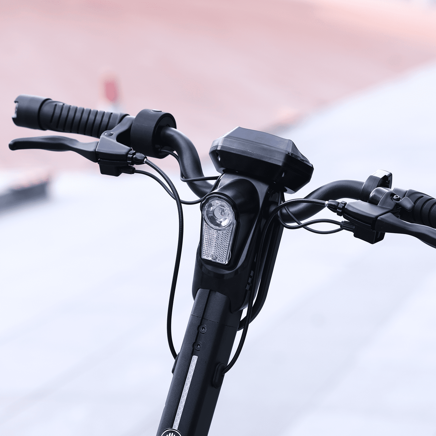 Close-up of a bicycle handlebar with controls and a light on a blurred background