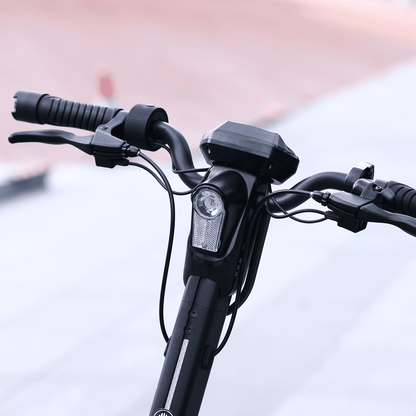 Close-up of a bicycle handlebar with controls and a light on a blurred background