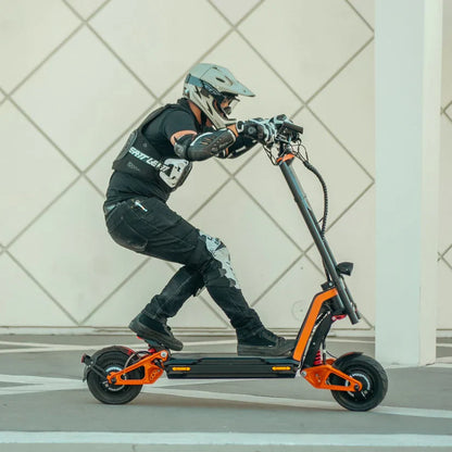 Person riding an electric scooter with a helmet and protective gear on a tiled floor.