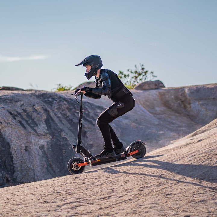 Person riding an Joyor S10 Electric Scooter on a rocky landscape