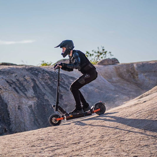 Person riding an electric scooter on a rocky landscape
