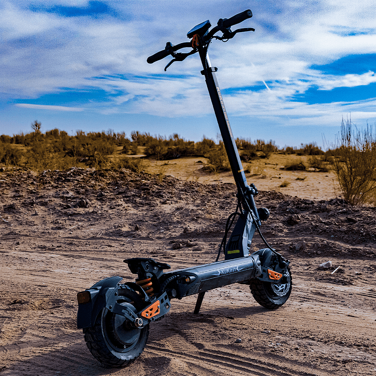 Electric scooter on a dirt road with a desert landscape and blue sky.
