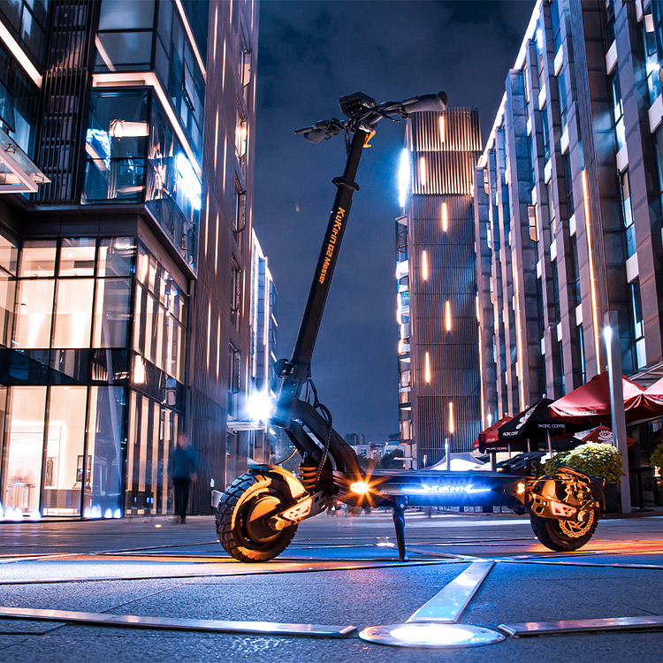 Modern electric scooter on a city street at night with illuminated buildings.