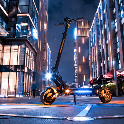 Modern electric scooter on a city street at night with illuminated buildings.