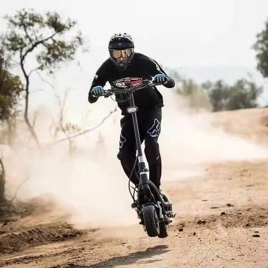 Person riding a scooter on a dirt road with trees in the background