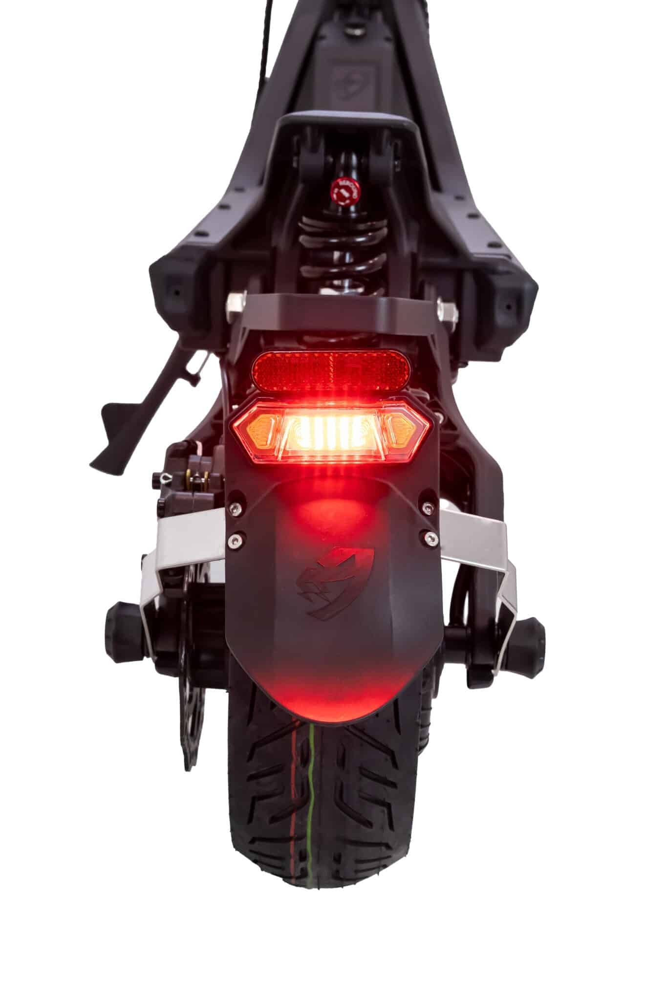 Close-up of a motorcycle's rear light and suspension system on a white background