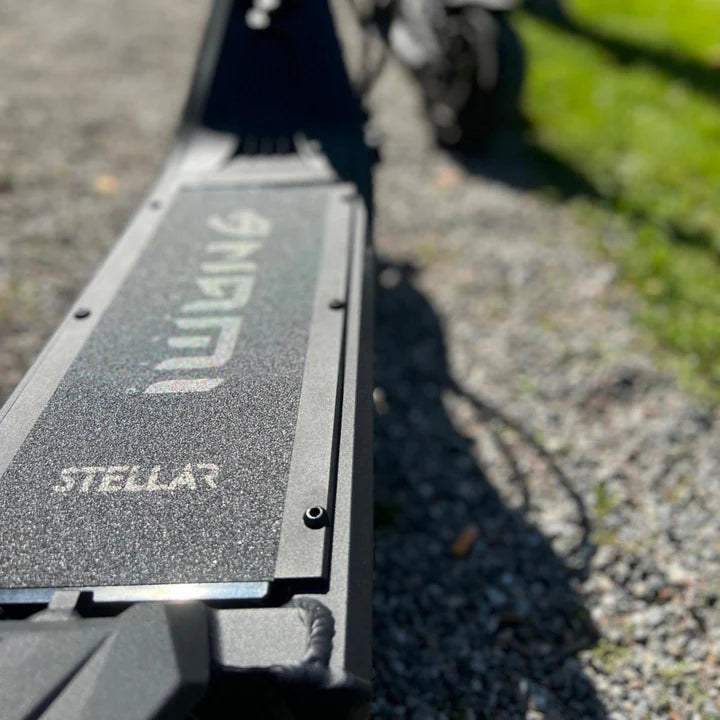 Close-up of a black scooter with 'Stellar' branding on a gravel surface.