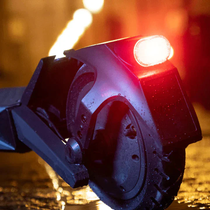 Close-up of a scooter wheel with a red light on a wet surface