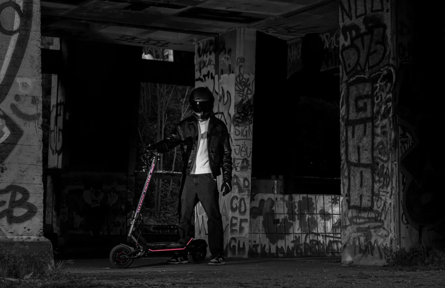 Person with a scooter in an abandoned building with graffiti