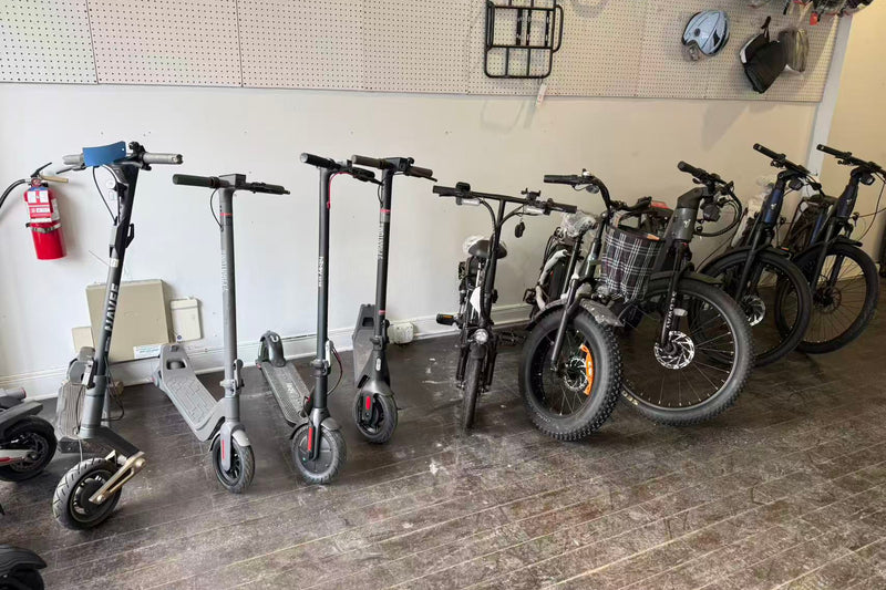 Row of electric scooters and bicycles in a storage area.