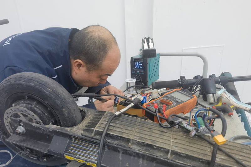 Person working on a mechanical or electronic component with tools and equipment.