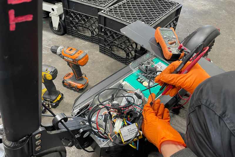 Person working on a vehicle's electrical system with tools and equipment in a garage.