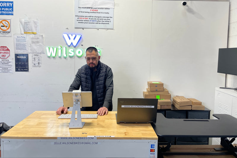 Person sitting at a desk with boxes and a laptop in an office setting, with Wilson's logo visible.