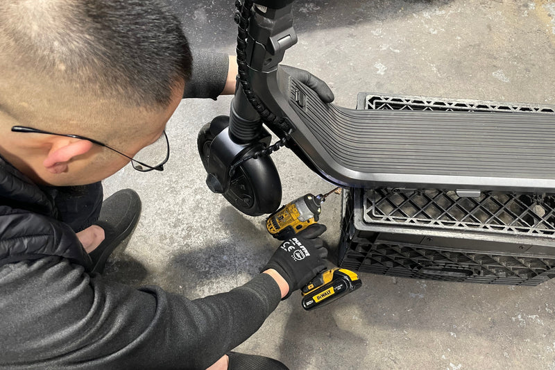 Person working on a scooter with tools on a concrete surface