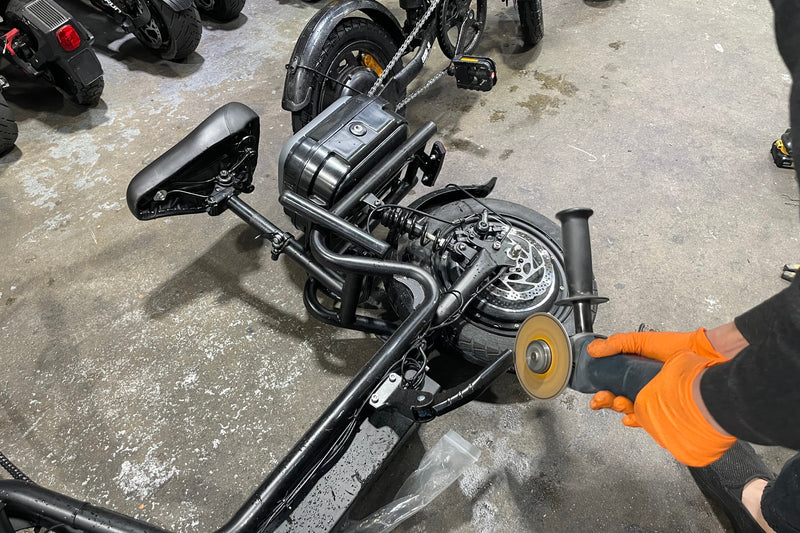 Person using a grinder on a motorcycle in an indoor setting