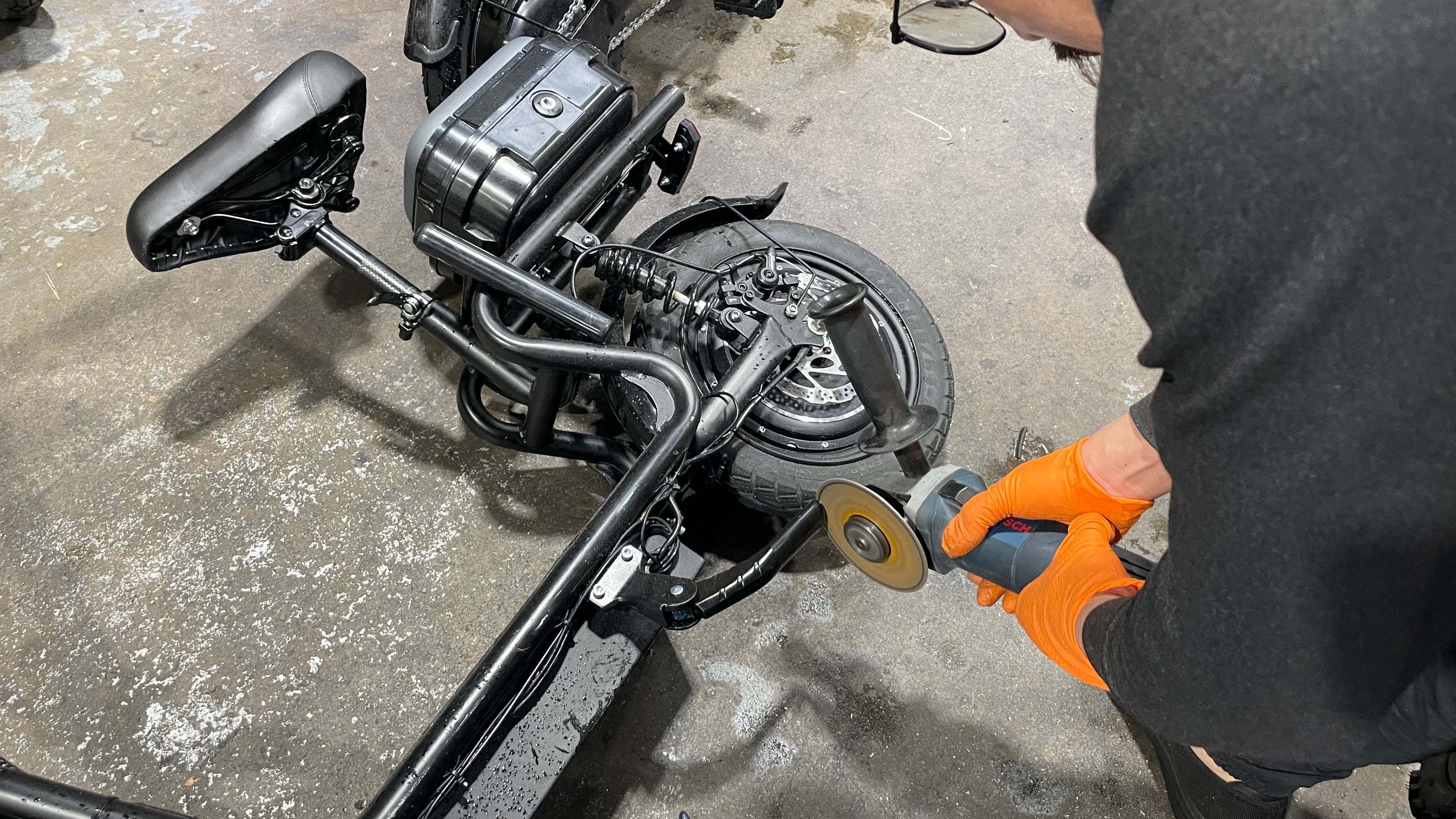 Person working on a scooter with a tool in an indoor setting