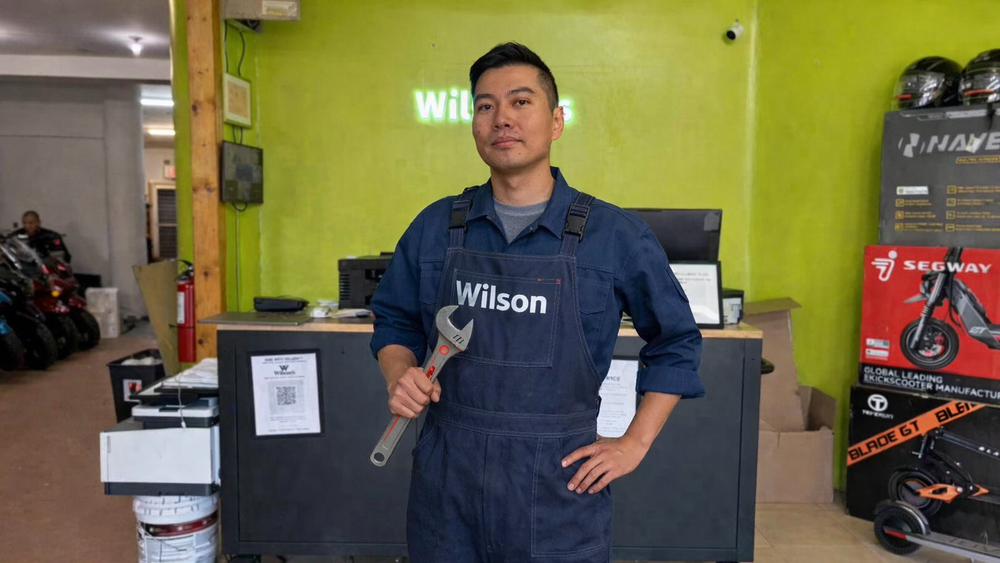 Person in a workshop wearing a Wilson uniform holding a wrench.