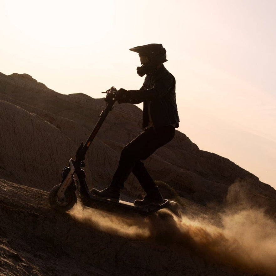 Person riding a Segway GT3 Pro Electric Scooter on a mountain with a sunset silhouette