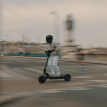 Person riding an electric scooter on a city street with blurred background